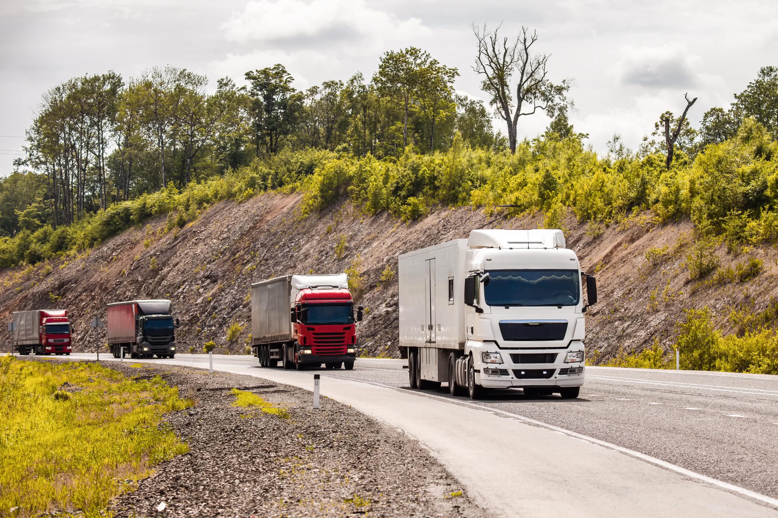 four-different-coloured-trucks-moving-by-road-min